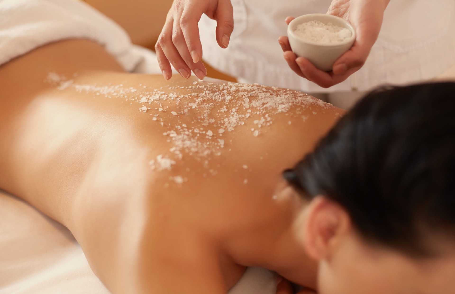 Person receiving a relaxing salt scrub massage on their back at a spa.