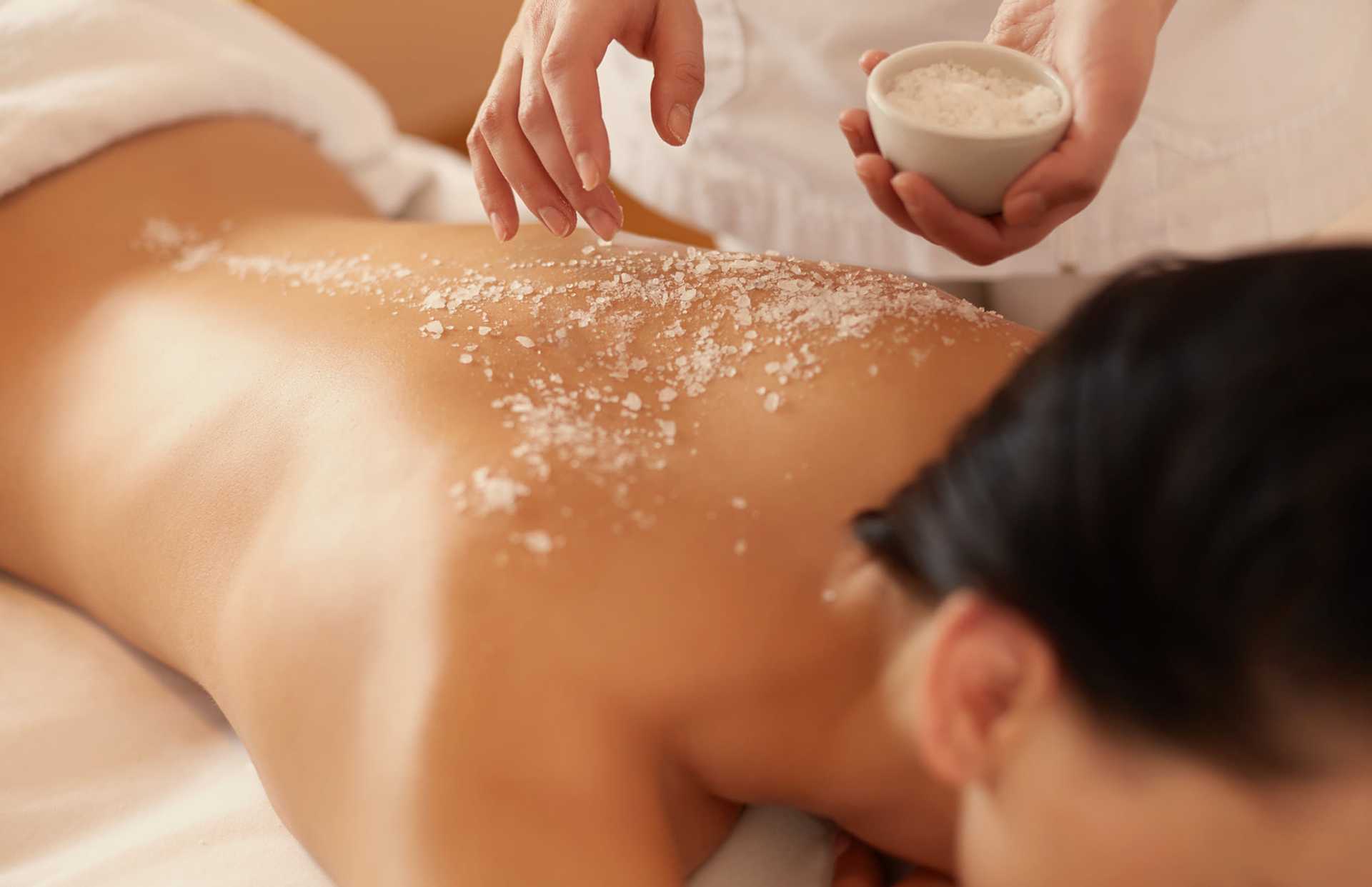 Person receiving a relaxing salt scrub massage on their back at a spa.