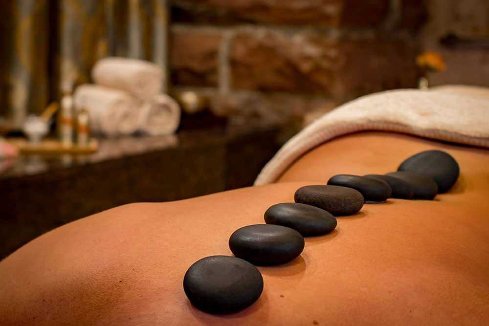 Hot stone massage therapy with smooth stones placed on a person's back for relaxation.