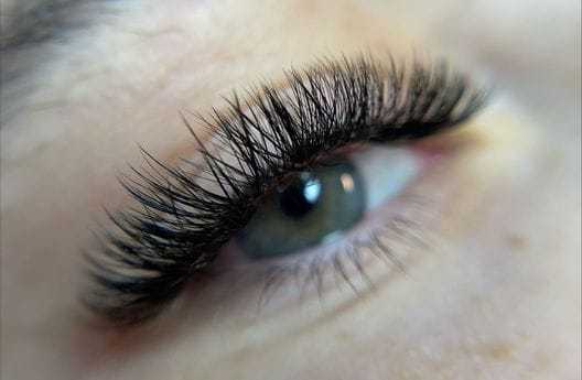Close-up of an eye with long, dark eyelashes and a clear iris.