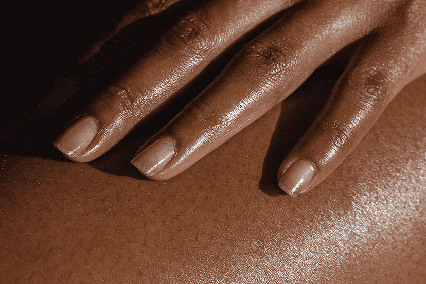 Close-up of a hand with manicured nails resting on smooth skin.