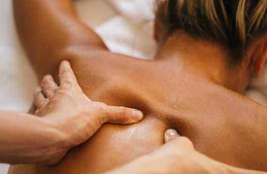 Person receiving a professional back massage, close-up of hands applying pressure on the back.
