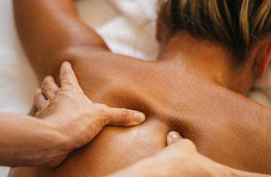 Person receiving a professional back massage, close-up of hands applying pressure on the back.