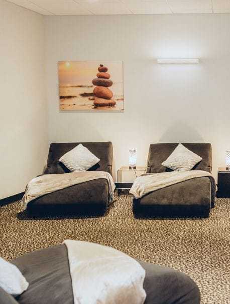Two cozy recliners with blankets in a tranquil room, featuring a serene painting of stacked stones.