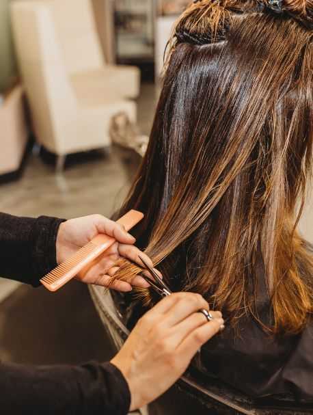 Hairdresser using a comb and scissors to trim a woman's hair in a salon.